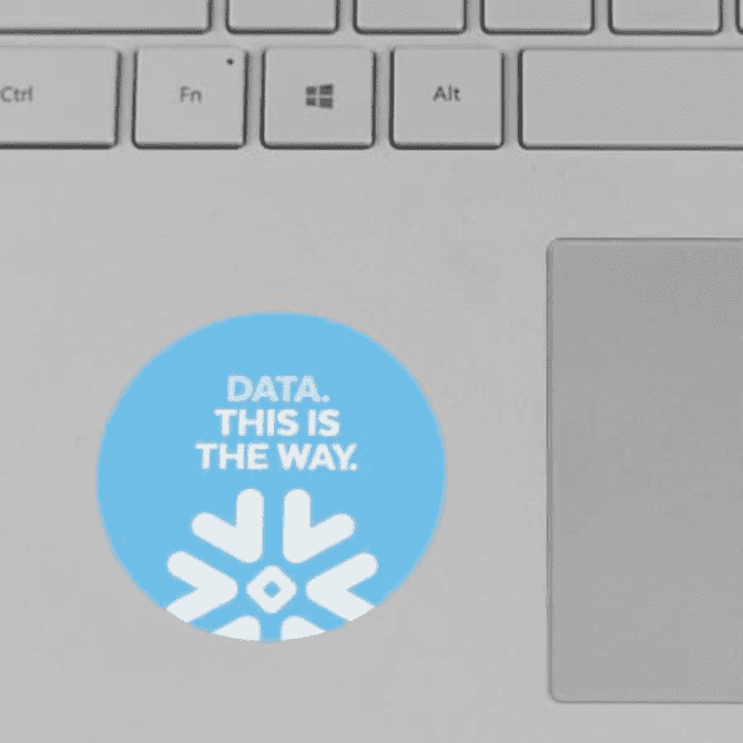 A round laptop sticker in light blue with a snowflake design and white text. A round laptop sticker in light blue with a snowflake design and white text.