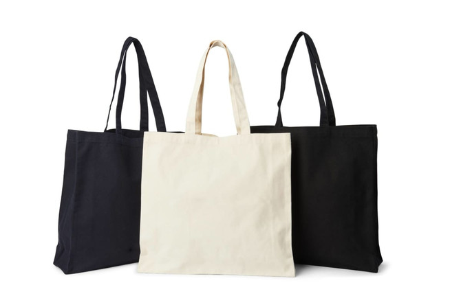 Three tote bags displayed: one black, one cream, and one black, featuring long handles and a simple design.