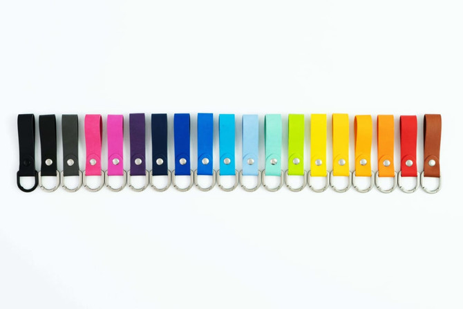 A variety of key fobs in different colours, each featuring a metal ring for attachment and a logo.