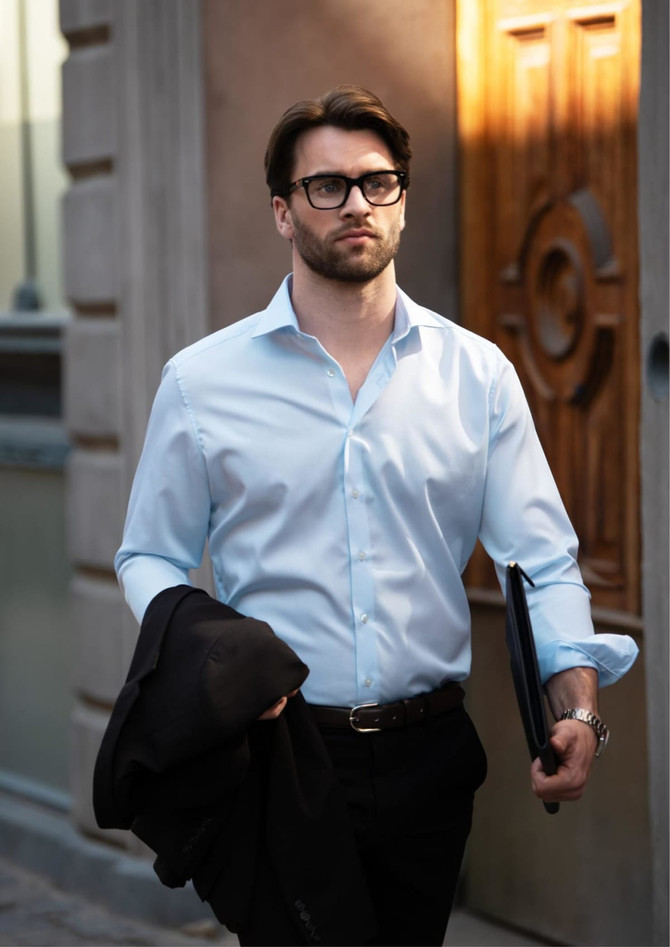 A stylish light blue button-up shirt worn by a man carrying a jacket and a folder, set against an urban backdrop.