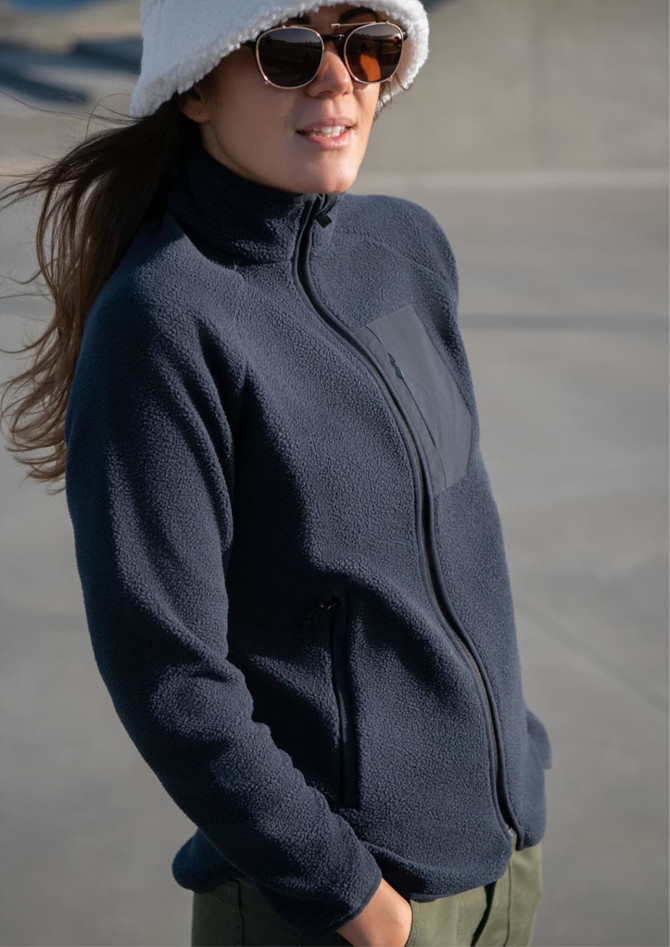 A navy women's jacket with a zip front, featuring a sleek design and side pockets, worn by a model.