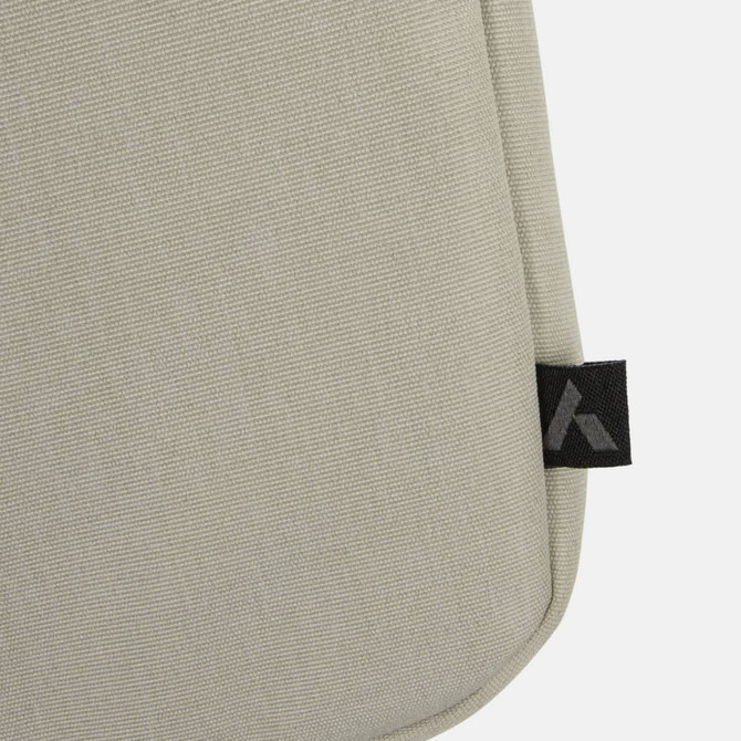 A beige laptop bag with a textured fabric, featuring a small logo tag on the side.