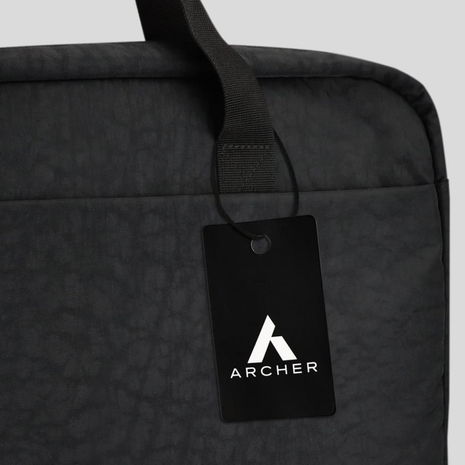A black laptop bag featuring a top handle and a tag with a logo. The material has a textured finish.