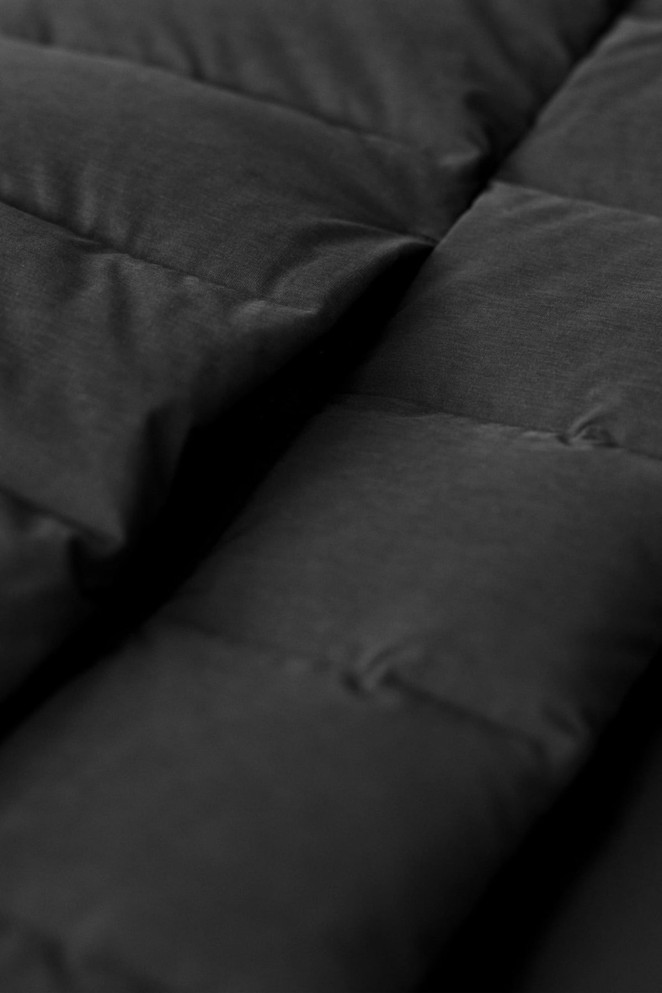 A close-up of a black down jacket featuring a quilted design with visible stitching and padded sections.