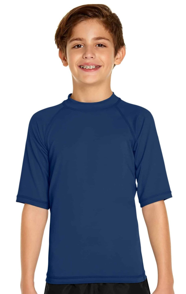 A young boy is wearing a navy blue short sleeve rashie designed for sun protection with a logo on it.