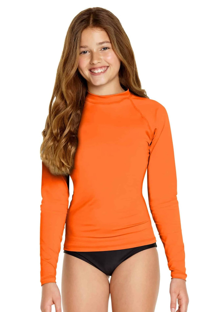 An orange long sleeve rashie with a fitted design, worn by a child, with a black bottom. The product features a logo.