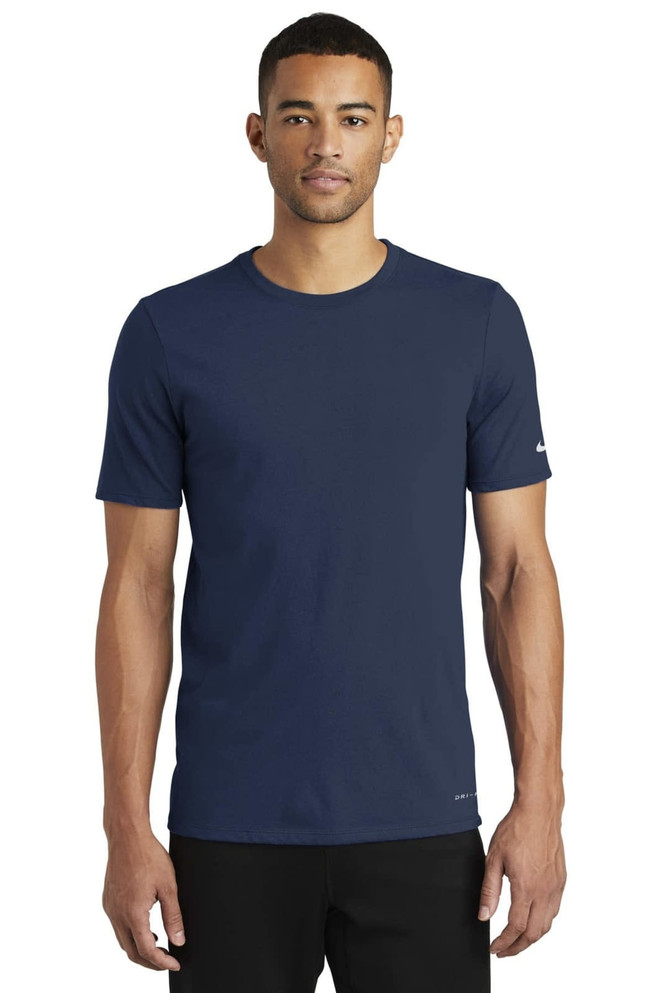 A navy blue Nike Dri-FIT Cotton/Poly T-shirt with short sleeves, featuring a logo on one sleeve. A navy blue Nike Dri-FIT Cotton/Poly T-shirt with short sleeves, featuring a logo on one sleeve.