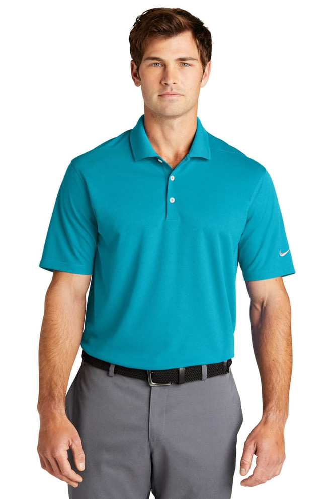 A turquoise Nike Dri-FIT Micro Pique 2.0 Polo shirt with a logo, displayed on a model wearing grey trousers.