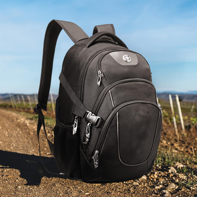 A black backpack with multiple compartments, set on a dirt path with vineyards in the background. It has a logo. A black backpack with multiple compartments, set on a dirt path with vineyards in the background. It has a logo.