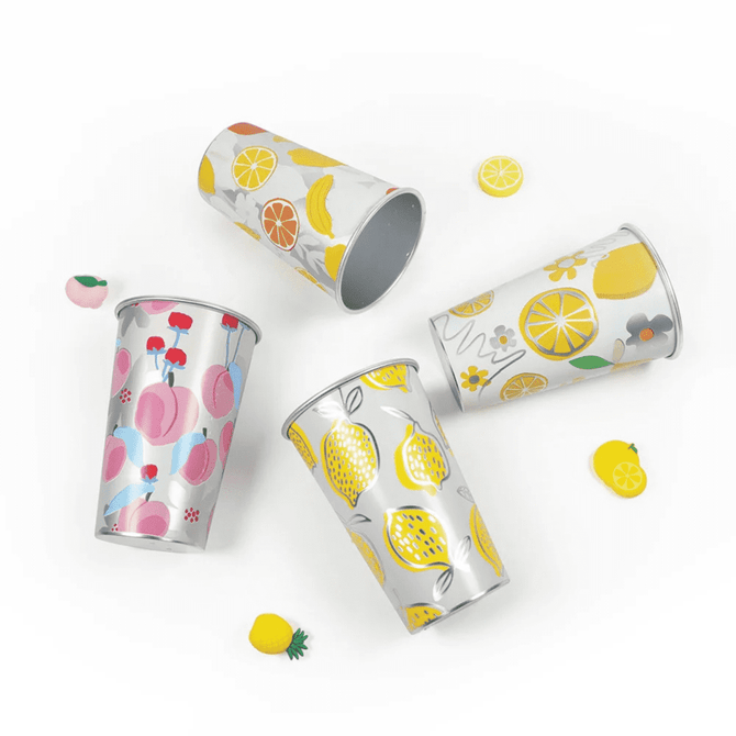 A set of four colourful, patterned cups featuring fruits like lemons, cherries, and peaches, with a shiny silver interior.