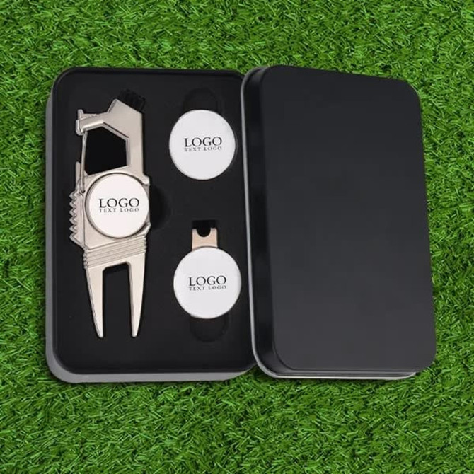 A silver divot tool set with two ball markers, presented in a black box, featuring a logo on the items.