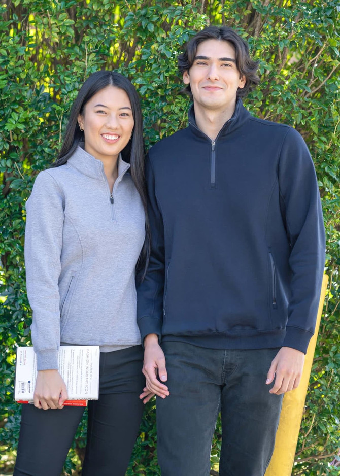 A woman in a grey half zip fleece and a man in a navy half zip fleece, both standing outdoors.