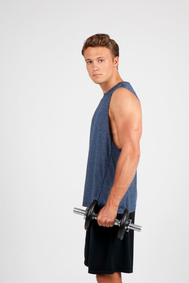 A sleeveless blue heather tee worn by a muscular man holding a dumbbell, set against a plain background.