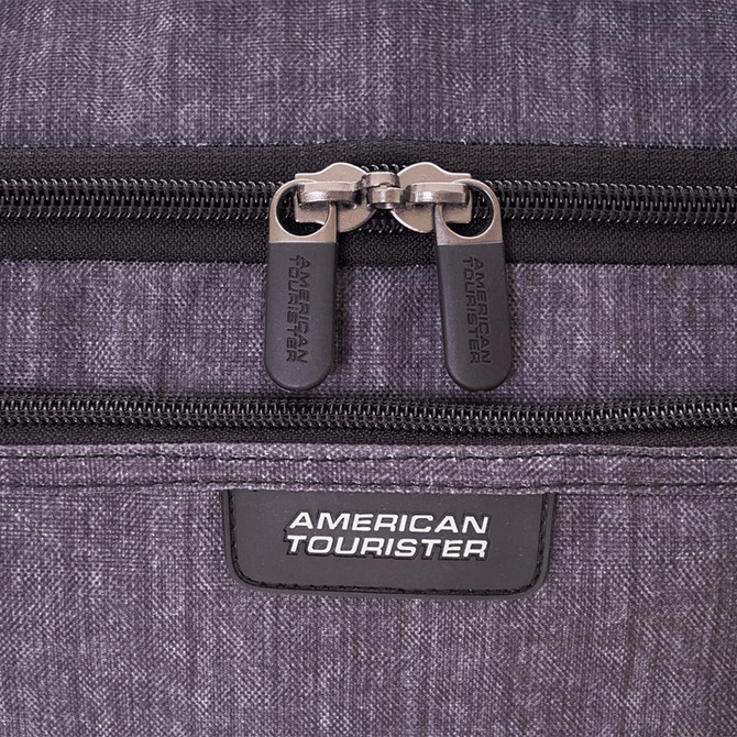 A grey duffle bag featuring dual zippers and a logo patch. The material has a textured appearance.