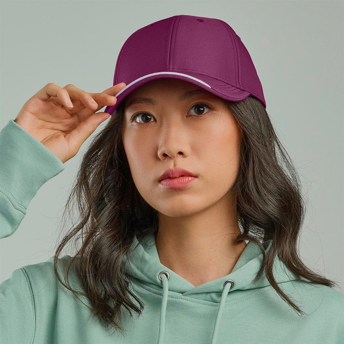 A purple cap with a contrasting peak, worn by a woman in a teal hoodie. Features a logo on the front.