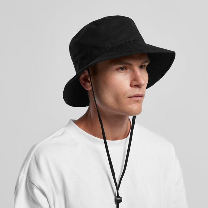 A black wide brim bucket hat with a chin strap, displayed on a model wearing a white shirt.