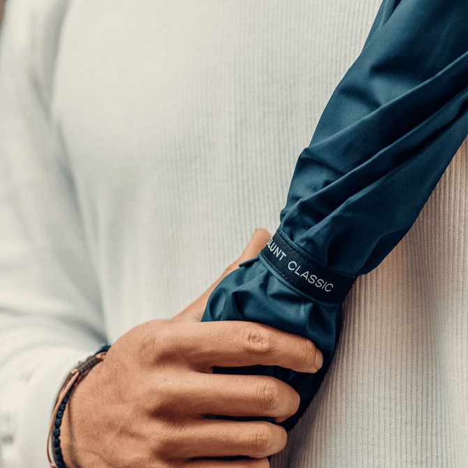 A navy blue umbrella held by a person wearing a light-coloured top, featuring a logo.