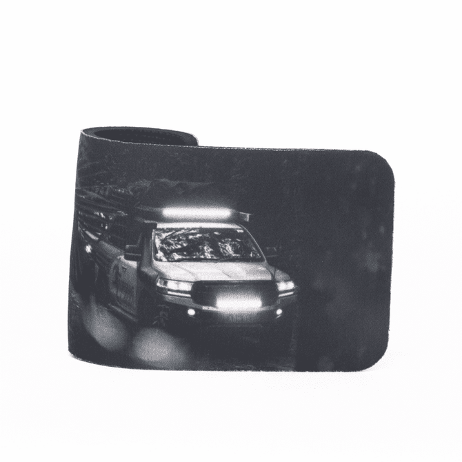 A stubby holder featuring a monochrome design of a vehicle, with a sleek black finish. It has a logo.