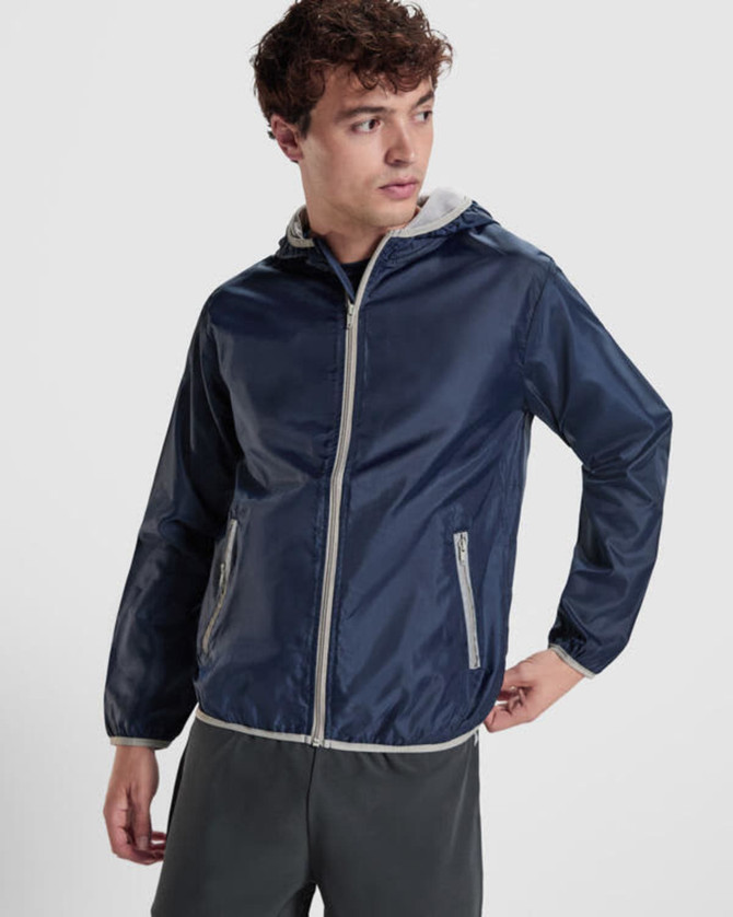 A navy windbreaker jacket with a grey hood, featuring zippered pockets and a front zipper, with a logo.