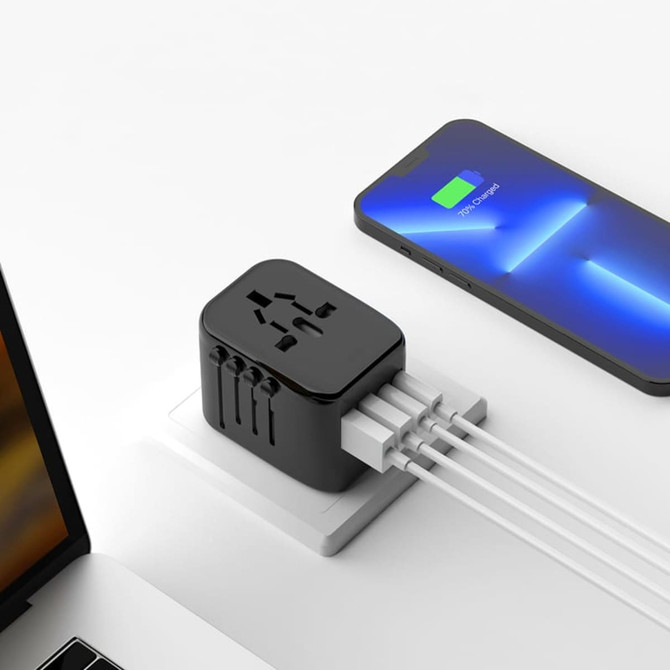 A black travel adaptor with multiple ports sits on a surface next to a smartphone, connected to various cables.