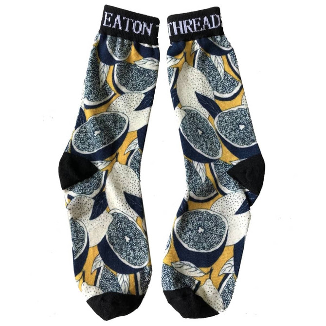 A pair of 3D printed dress socks featuring a vibrant citrus pattern in yellow, navy, and black.