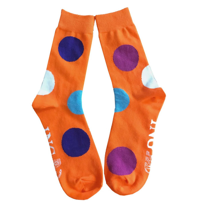 Bright orange socks featuring large multicoloured polka dots in blue, purple, and white. The design is playful and vibrant.