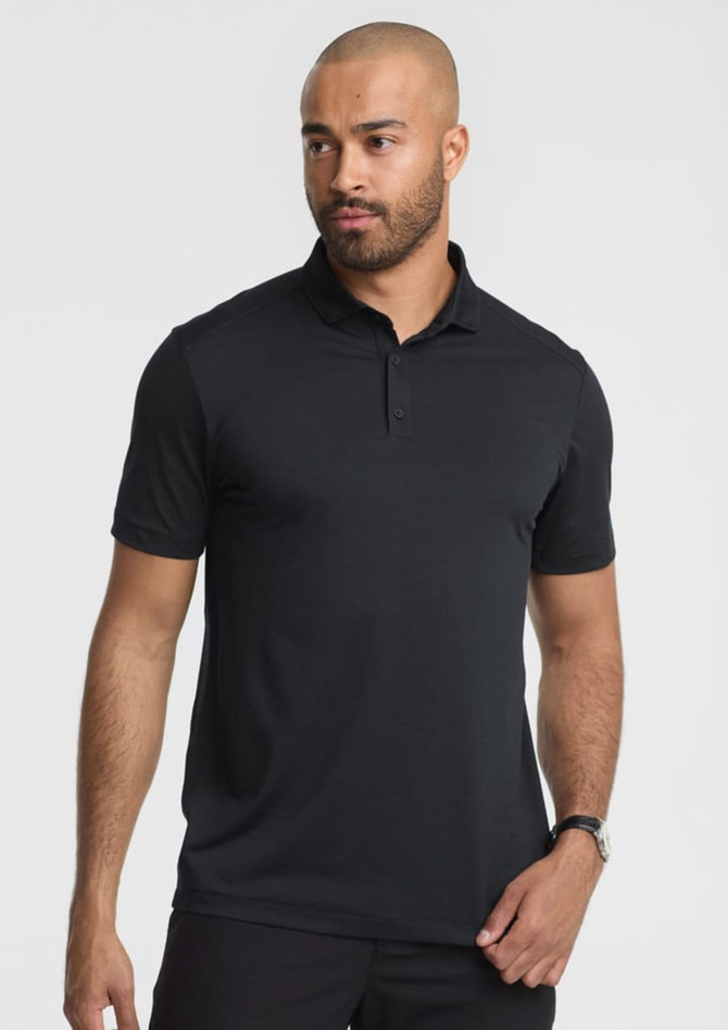 A men's short sleeve polo in black, featuring a collar and a logo. Model is posing.