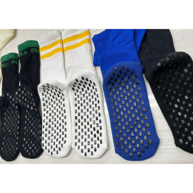 A selection of Crew Grip socks in black, white, blue, and green, featuring rubber grip soles and a logo.