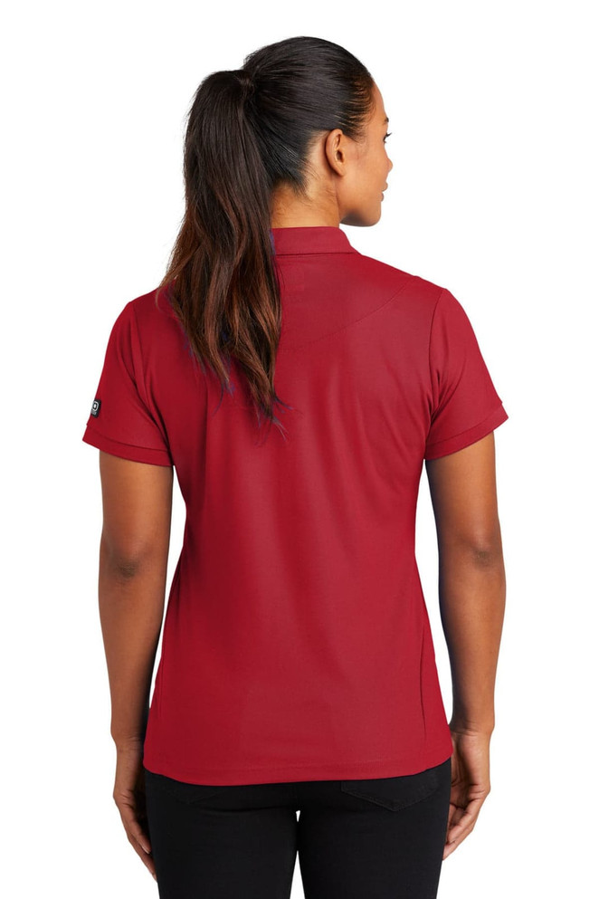 A red OGIO Jewel Polo shirt displayed on a model from the back, featuring short sleeves and a fitted design.
