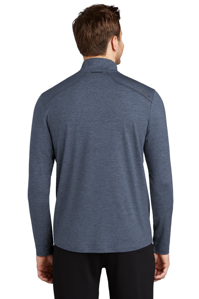A man is wearing a navy blue OGIO ENDURANCE Force 1/4-Zip top, featuring a collar and long sleeves, with a logo on the back.