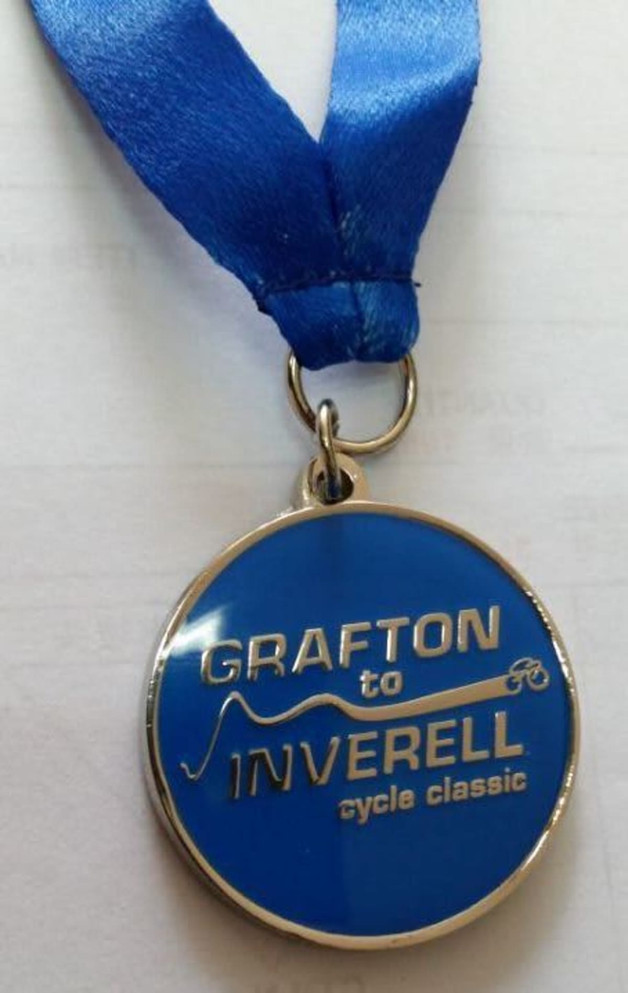 A blue soft enamel medal with an epoxy finish, featuring a silver loop and ribbon. It includes a logo and text.