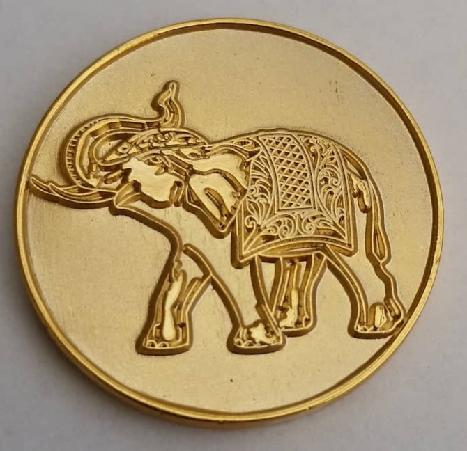 A gold lapel pin featuring an intricately designed elephant. The pin has a shiny gold finish.