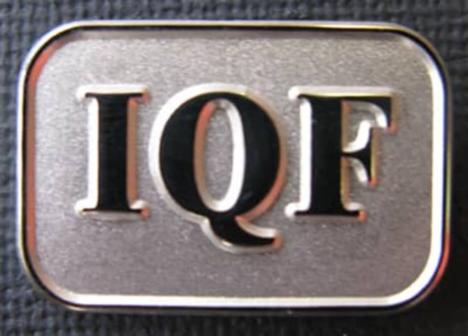 A silver lapel pin with a rectangular shape featuring the letters "IQF" in a bold font.