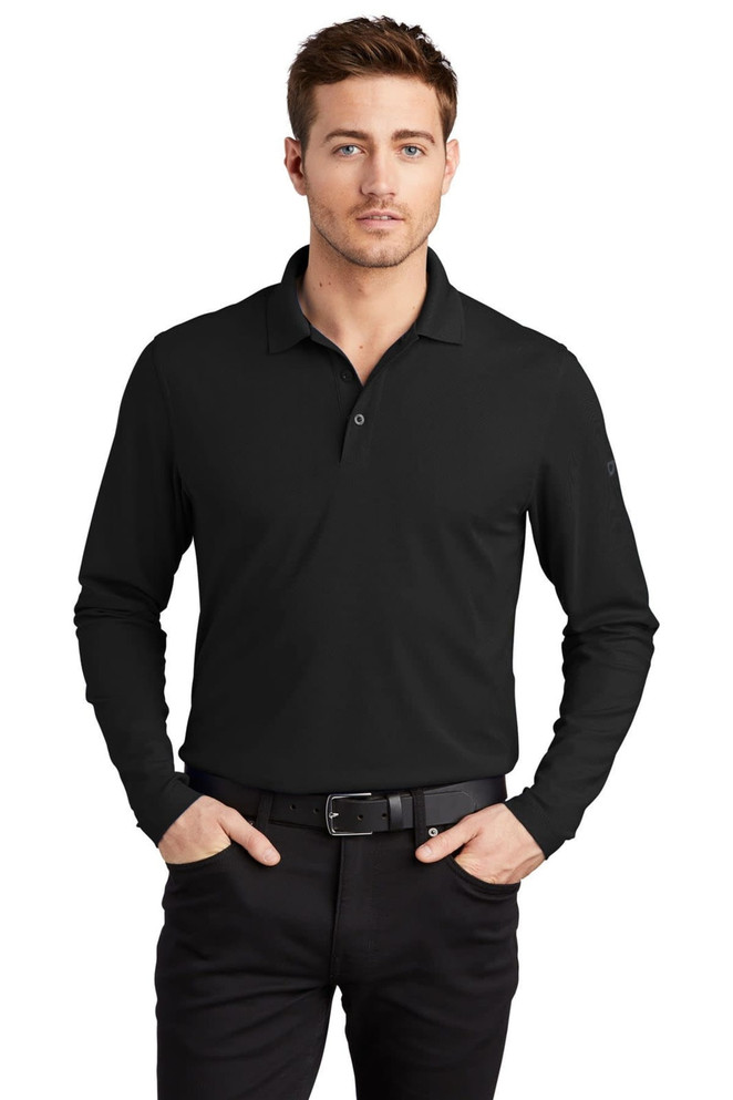 A black long sleeve shirt with a collar, featuring a logo, worn by a model with cropped hair and a belt.
