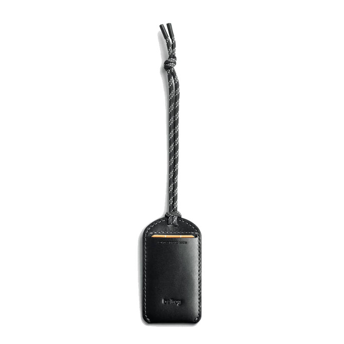 A black leather luggage tag features a braided strap and a logo. The design is sleek and minimalist.