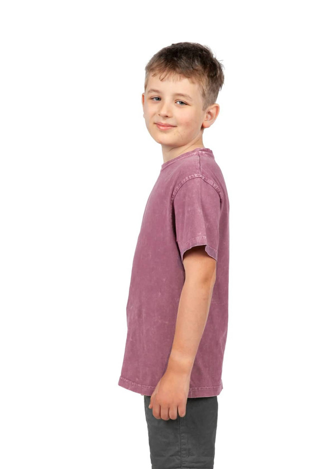 A boy stands sideways wearing a stone wash T-shirt in a soft burgundy colour. The shirt features a simple design and a logo.