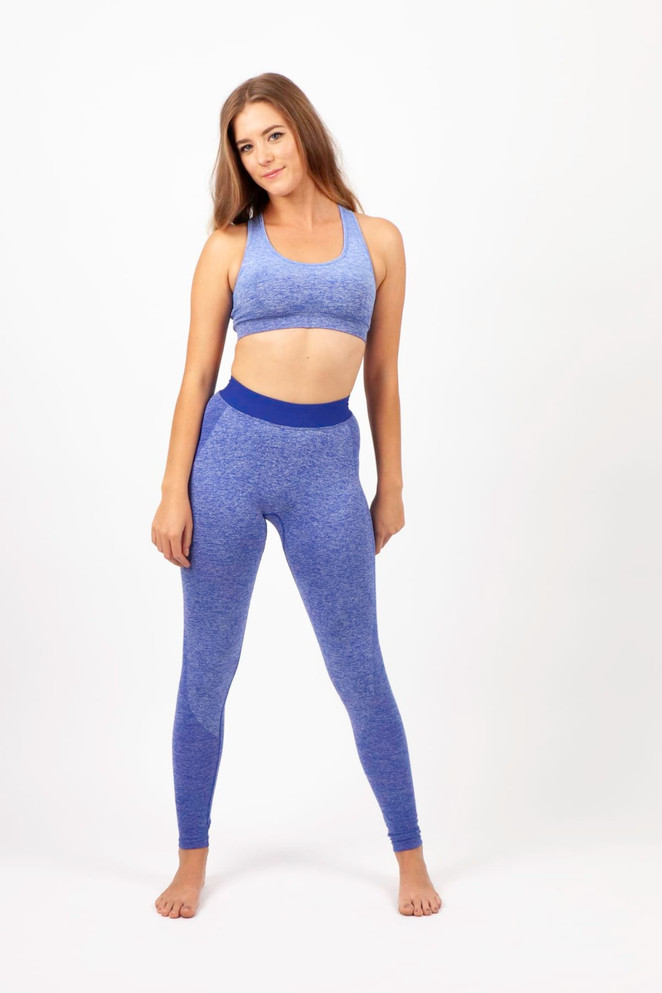 A model poses in a light purple seamless crop top and matching leggings, featuring a logo on the crop top.
