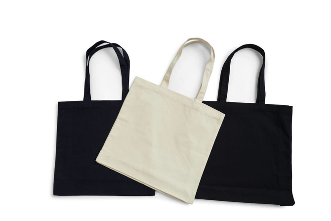 Three tote bags in black and cream, featuring long handles and a simple design, one bag in the front is cream.