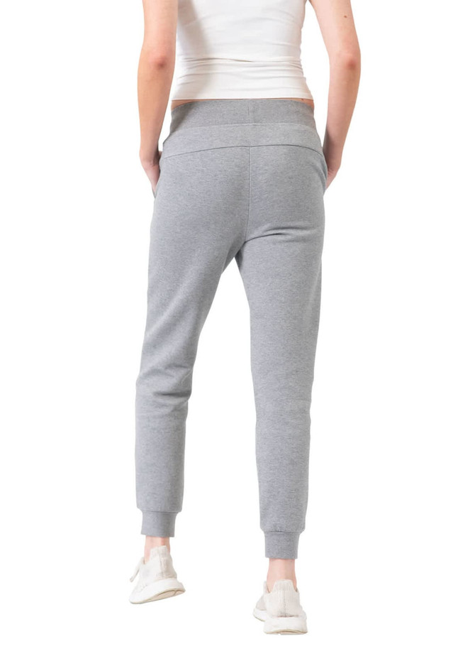 Grey women's track pants with a slim fit and pockets, paired with a fitted white top and shoes.