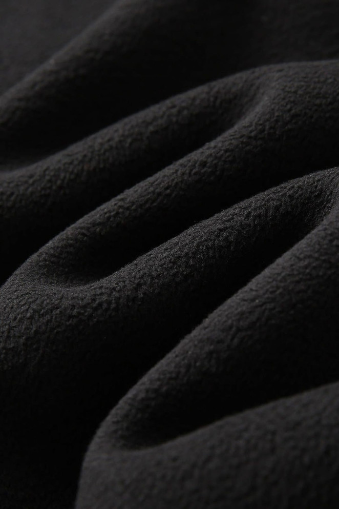 A close-up of black polar fleece fabric with a soft, textured surface, showcasing its warmth and comfort.