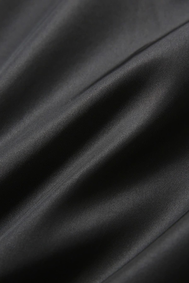 A close-up of a smooth, black wool blend fabric showcasing its soft texture and elegant finish.