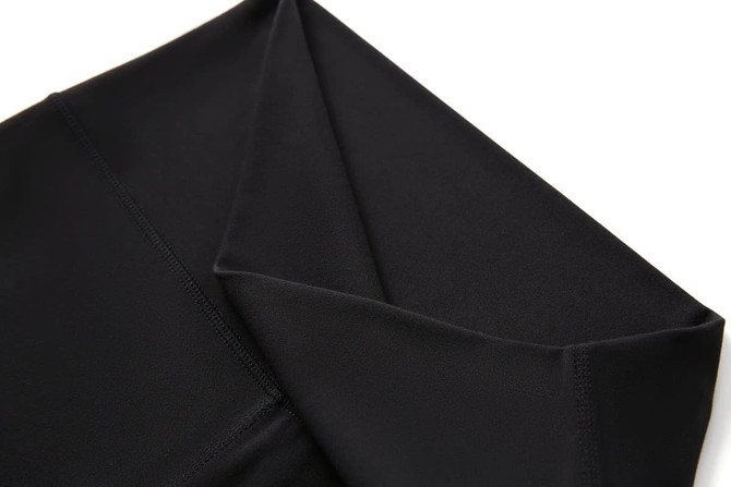 A pair of black women's high rise legging shorts, displaying the fabric and waistband design. There is a logo present.