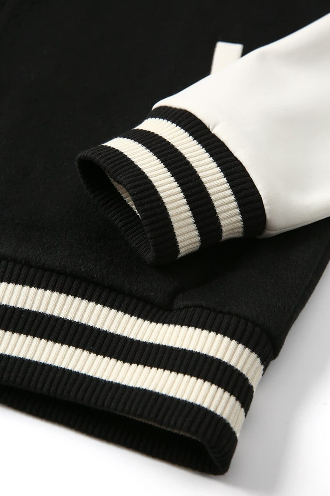 A black and white wool blend varsity jacket featuring ribbed cuffs with monochrome stripes. Includes a logo.