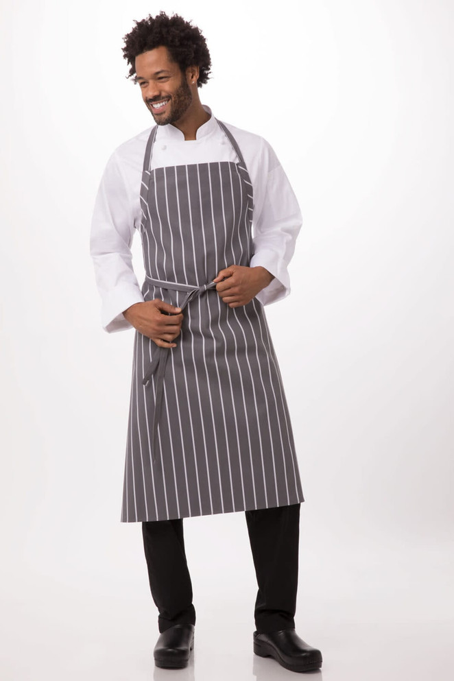 A chef apron in grey with white stripes, worn by a smiling man in a white shirt and black trousers.