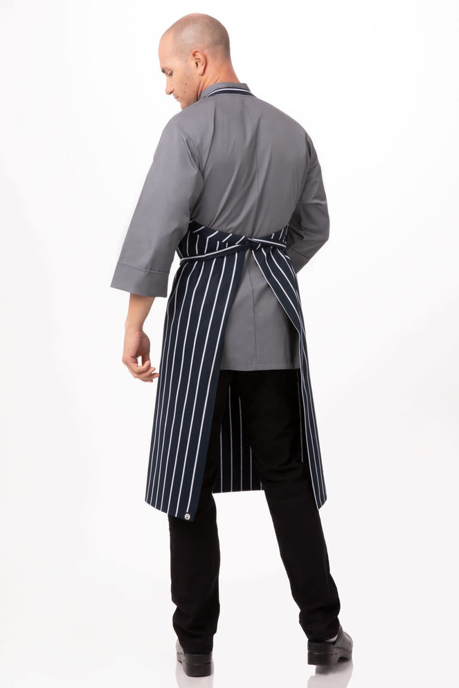 A grey chef apron with navy stripes, featuring half sleeves and a tied back, worn by a male model.