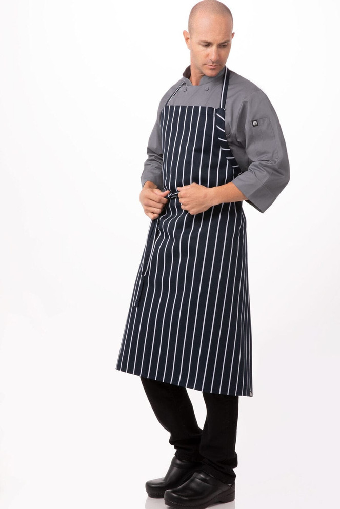 A navy and white striped chef apron is worn by a model in a grey shirt and black pants, featuring a logo.