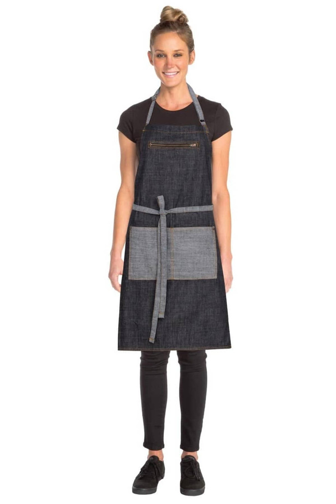 A woman models a dark denim apron with a grey pocket and straps, featuring a logo on the front.
