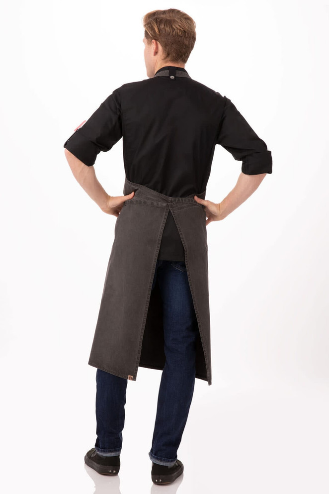 A dark grey chef's bib apron with a split back, worn by a person from behind, featuring a logo.