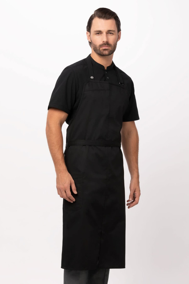 A black bib apron worn by a model, featuring adjustable straps and a logo on the front.