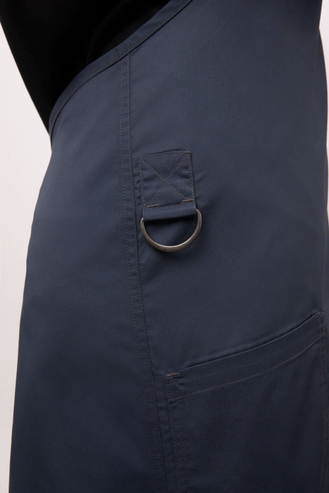 A navy blue bib apron featuring a pocket with a metal ring and a sleek design.